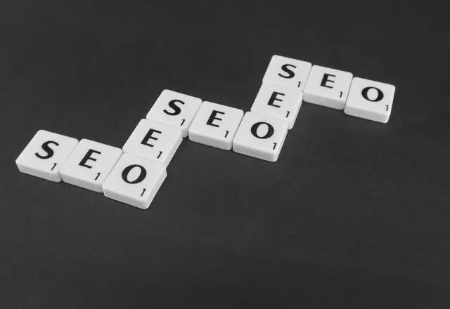 Three sets of letter tiles spelling out "SEO" arranged in an upward-stepping, staircase pattern on a dark surface.