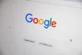 Google Search homepage on a digital screen featuring the iconic colorful logo, search bar, and action buttons.