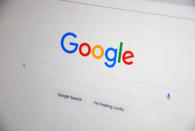 Google Search homepage on a digital screen featuring the iconic colorful logo, search bar, and action buttons.